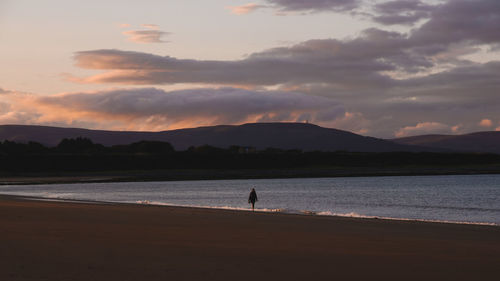 Silhouette person on beach against sky during sunset