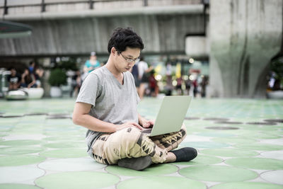 Young man using mobile phone while sitting outdoors