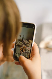 Video blog. a young woman is filming kitchen goods for her online store on her phone camera.