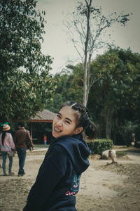 Portrait of a smiling young woman against trees