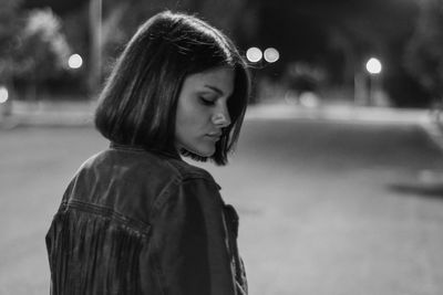 Portrait of young woman looking away while standing on street