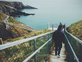 Rear view of woman standing by railing against sea