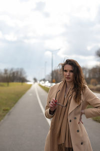 Young woman standing on road against sky