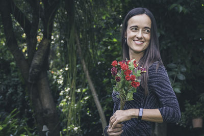 Portrait of young woman standing against trees