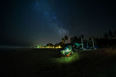 Illuminated beach against sky at night