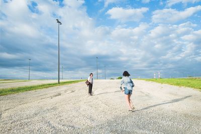 Rear view of people walking on road against sky