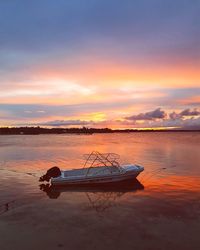 Boat moored on sea against sky during sunset