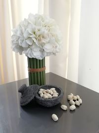 Close-up of pistachios by flowers in vase on table