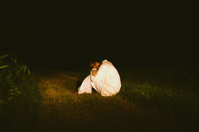 Man sitting on field at night