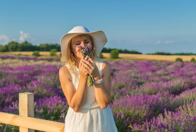 Woman smelling flowers wearing hat at farm