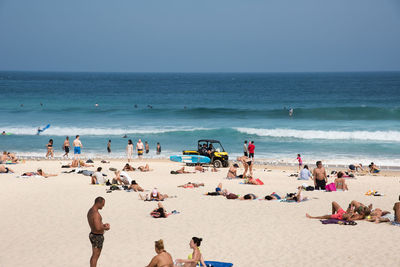 Crowd at beach against sky