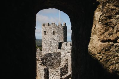 Old ruin building against sky seen through window