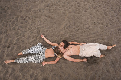 High angle view of happy couple lying on sand at beach