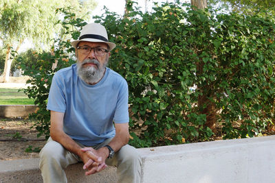 Portrait of senior man wearing hat standing against trees