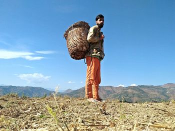 Man with arms raised on mountain against sky