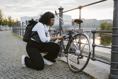 Businesswoman locking bicycle on railing at promenade in city