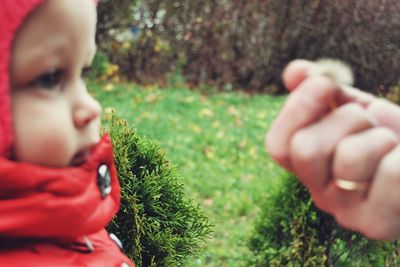 Cropped image of hand by boy on field