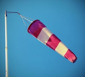 Low angle view of flags against clear blue sky