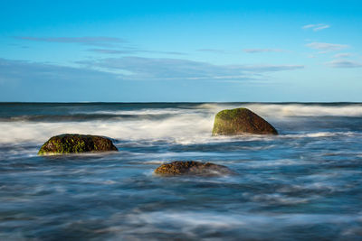 Scenic view of rocks in sea against sky