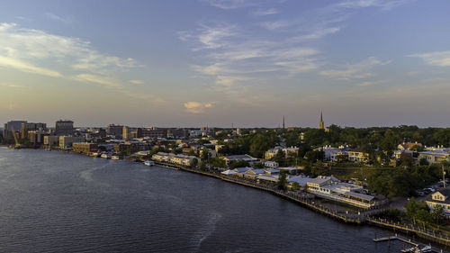 River amidst buildings in city against sky during sunset