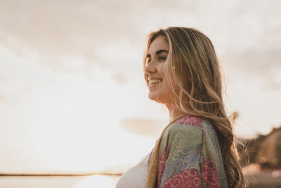 Side view of young woman standing against sky