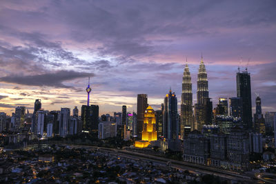 Illuminated cityscape against sky during sunset