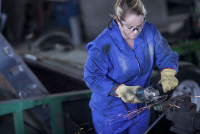 Woman using angle grinder in workshop
