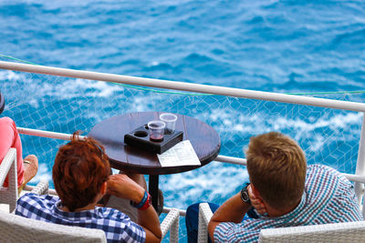 People relaxing in swimming pool against sea