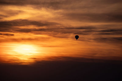 Hot air balloons flying against sky during sunset