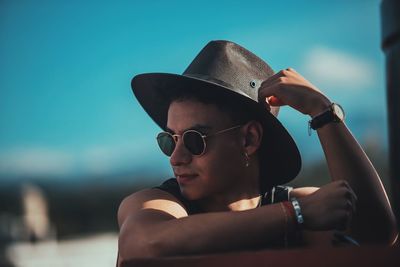 Close-up of young man wearing sunglasses against blue sky
