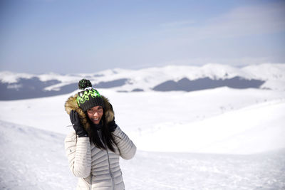 Woman standing on snow covered mountain against sky