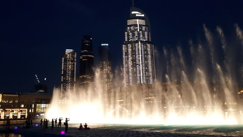 Illuminated buildings against sky at night