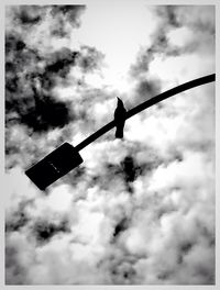 Low angle view of crane against cloudy sky