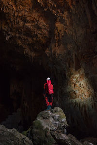 Rear view of man standing on rock in cave