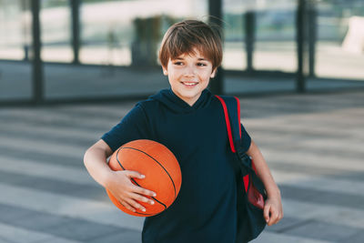 Portrait of smiling boy holding ball against blurred background