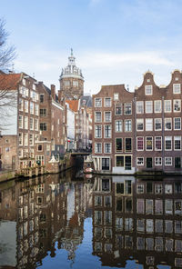 Canal amidst buildings in city against sky