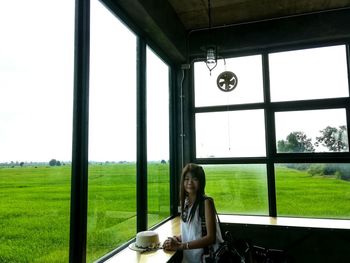 Portrait of smiling woman standing by window