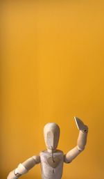 Close-up of wooden figurine against yellow background