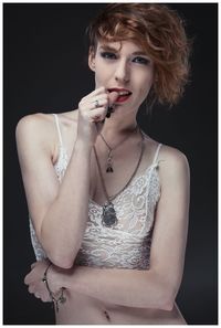 Portrait of young woman against black background