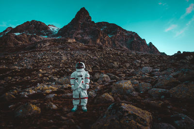 Rear view of man standing on rock against sky