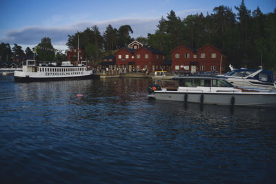 Sailboats moored on river by houses against sky