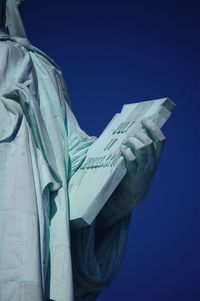 Low angle view of liberty statue against clear blue sky