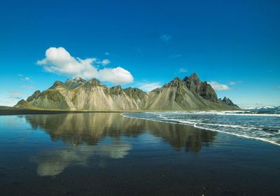 Scenic view of lake and mountains against blue sky