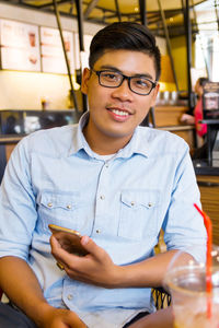 Portrait of young man using mobile phone at cafe