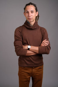 Portrait of young man standing against gray background