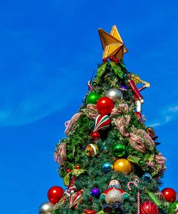 Low angle view of christmas tree against blue sky