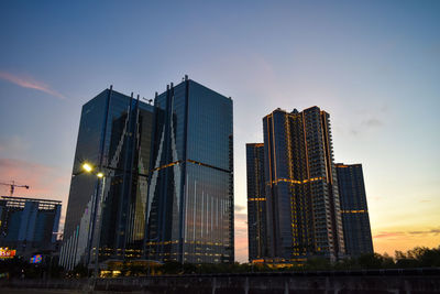 Modern buildings in city against sky at dusk