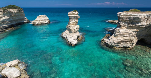 Panoramic view of rocks and sea against blue sky