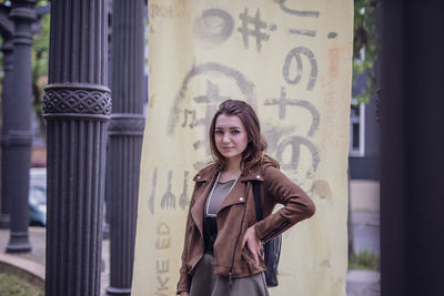 Portrait of smiling young woman standing against columns