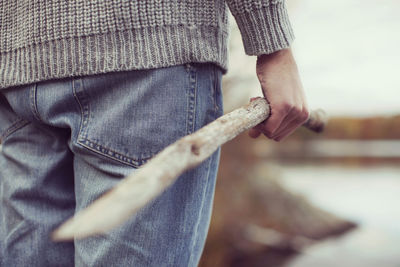 Midsection of man holding stick